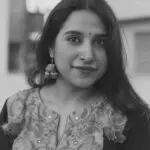 Black and white portrait of a smiling woman in Mumbai showcasing traditional jewelry and floral attire.